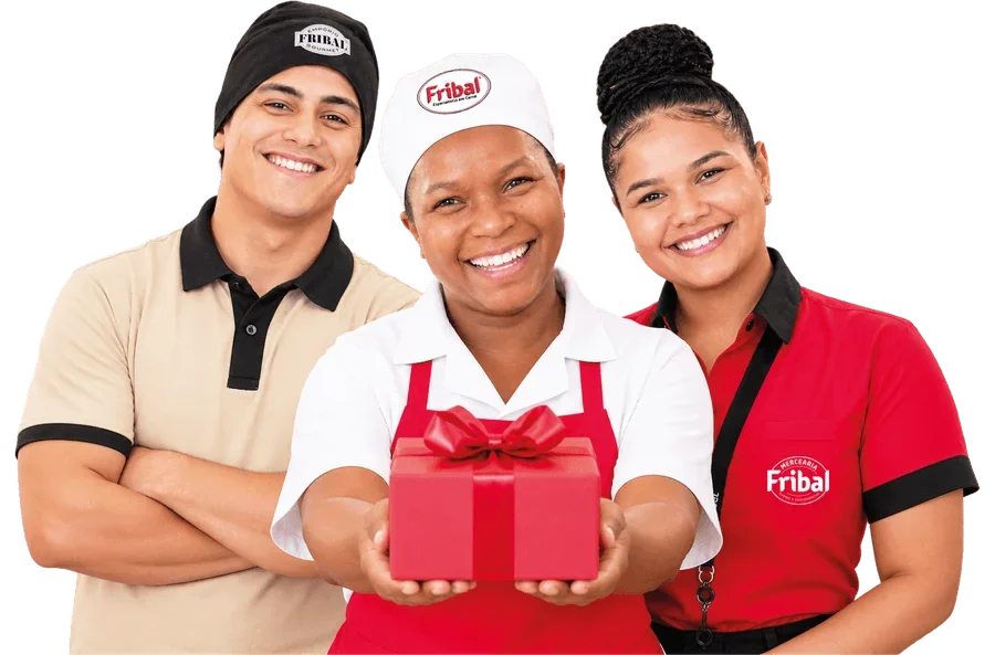 Três colaboradores da Fribal sorrindo, a do centro segurando um presente vermelho